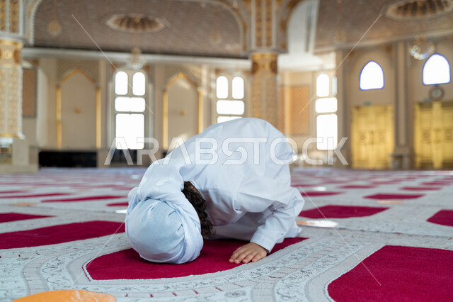 ولد صغير عربي خليجي إماراتي في أحد المساجد العربية، أداء فريضة الصلاة ، السجود في الصلاة ، العبادة والتقرب الى الله ، أماكن إسلامية مقدسة ، مفهوم أركان الإسلام ، إسلاميات وعبادة