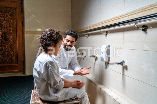 رجل عربي خليجي إماراتي وإبنه في أماكن مخصصة للوضوء في أحد المساجد العربية ، تعلم كيفية الوضوء للأطفال ، الطهارة والوضوء ، مغاسل الوضوء ، أحواض ومغاسل مخصصة للوضوء ، مفهوم أركان الوضوء