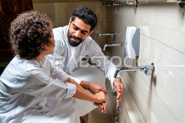 رجل عربي خليجي إماراتي وإبنه في أماكن مخصصة للوضوء في أحد المساجد العربية ، تعلم كيفية الوضوء للأطفال ، الطهارة والوضوء ، مغاسل الوضوء ، أحواض ومغاسل مخصصة للوضوء ، مفهوم أركان الوضوء