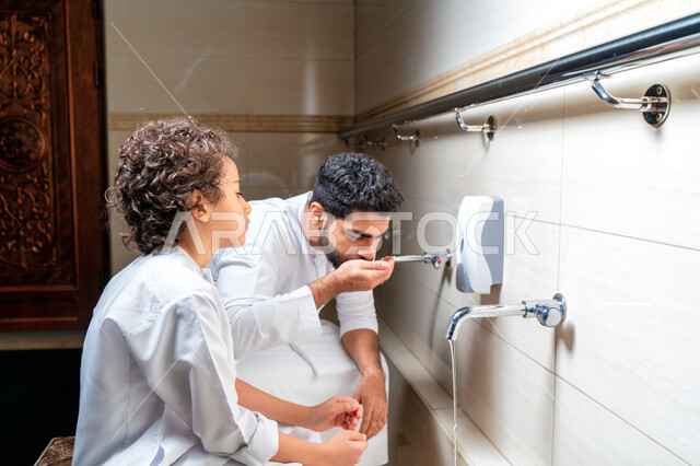 رجل عربي خليجي إماراتي وإبنه في أماكن مخصصة للوضوء في أحد المساجد العربية ، تعلم كيفية الوضوء للأطفال ، الطهارة والوضوء ، مغاسل الوضوء ، أحواض ومغاسل مخصصة للوضوء ، مفهوم أركان الوضوء