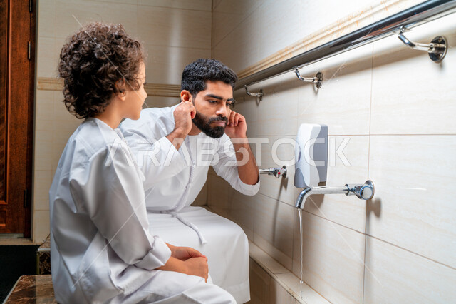 رجل عربي خليجي إماراتي وإبنه في أماكن مخصصة للوضوء في أحد المساجد العربية ، تعلم كيفية الوضوء للأطفال ، الطهارة والوضوء ، مغاسل الوضوء ، أحواض ومغاسل مخصصة للوضوء ، مفهوم أركان الوضوء