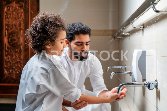 رجل عربي خليجي إماراتي وإبنه في أماكن مخصصة للوضوء في أحد المساجد العربية ، تعلم كيفية الوضوء للأطفال ، الطهارة والوضوء ، مغاسل الوضوء ، أحواض ومغاسل مخصصة للوضوء ، مفهوم أركان الوضوء