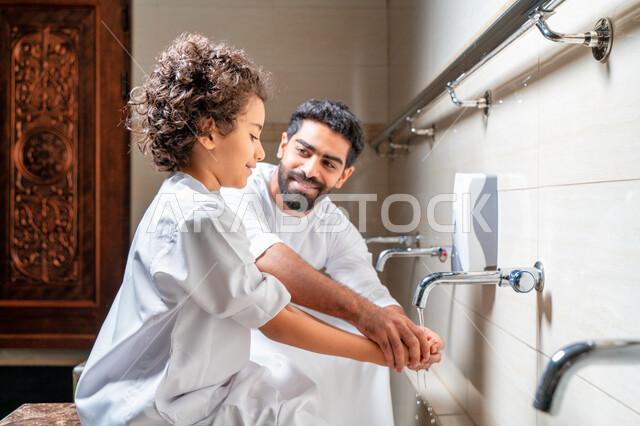 رجل عربي خليجي إماراتي وإبنه في أماكن مخصصة للوضوء في أحد المساجد العربية ، تعلم كيفية الوضوء للأطفال ، الطهارة والوضوء ، مغاسل الوضوء ، أحواض ومغاسل مخصصة للوضوء ، مفهوم أركان الوضوء