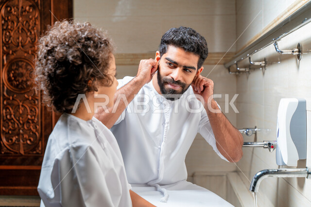 An Emirati Arab Gulf man and his son in places designated for ablution in an Arab mosque, learning how to ablution for children, purity and ablution, ablution sinks, basins and sinks for ablution, the concept of the pillars of ablution