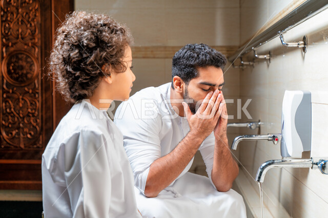 رجل عربي خليجي إماراتي وإبنه في أماكن مخصصة للوضوء في أحد المساجد العربية ، تعلم كيفية الوضوء للأطفال ، الطهارة والوضوء ، مغاسل الوضوء ، أحواض ومغاسل مخصصة للوضوء ، مفهوم أركان الوضوء