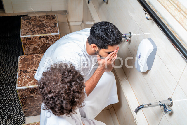 رجل عربي خليجي إماراتي وإبنه في أماكن مخصصة للوضوء في أحد المساجد العربية ، تعلم كيفية الوضوء للأطفال ، الطهارة والوضوء ، مغاسل الوضوء ، أحواض ومغاسل مخصصة للوضوء ، مفهوم أركان الوضوء
