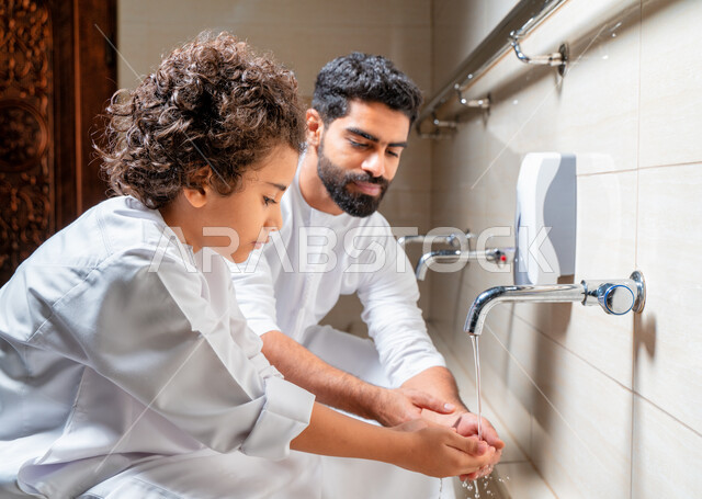 رجل عربي خليجي إماراتي وإبنه في أماكن مخصصة للوضوء في أحد المساجد العربية ، تعلم كيفية الوضوء للأطفال ، الطهارة والوضوء ، مغاسل الوضوء ، أحواض ومغاسل مخصصة للوضوء ، مفهوم أركان الوضوء