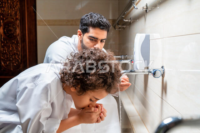 An Emirati Arab Gulf man and his son in places designated for ablution in an Arab mosque, learning how to ablution for children, purity and ablution, ablution sinks, basins and sinks for ablution, the concept of the pillars of ablution