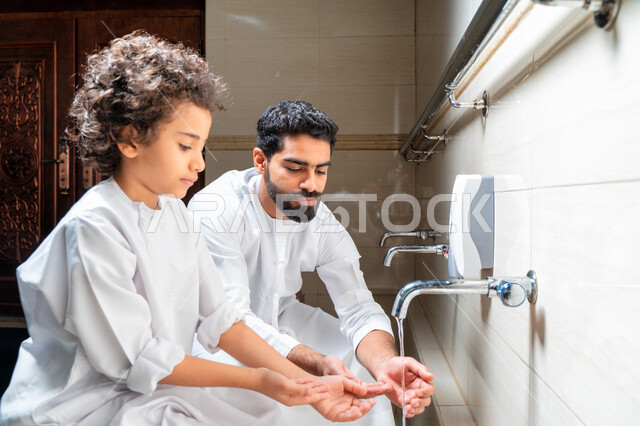 رجل عربي خليجي إماراتي وإبنه في أماكن مخصصة للوضوء في أحد المساجد العربية ، تعلم كيفية الوضوء للأطفال ، الطهارة والوضوء ، مغاسل الوضوء ، أحواض ومغاسل مخصصة للوضوء ، مفهوم أركان الوضوء