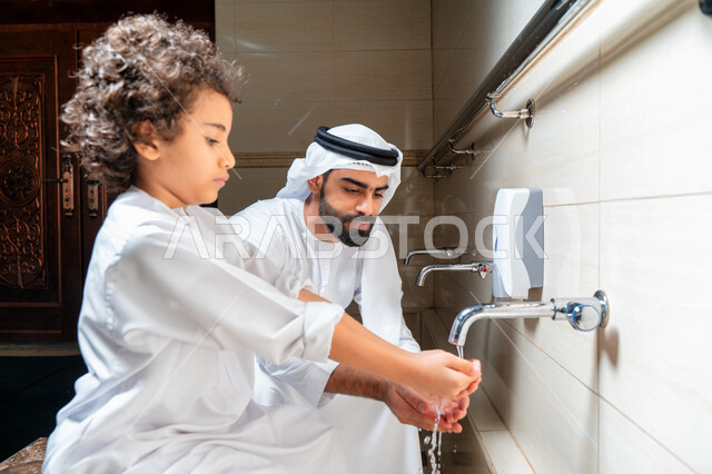 رجل عربي خليجي إماراتي وإبنه في أماكن مخصصة للوضوء في أحد المساجد العربية ، تعلم كيفية الوضوء للأطفال ، الطهارة والوضوء ، مغاسل الوضوء ، أحواض ومغاسل مخصصة للوضوء ، مفهوم أركان الوضوء