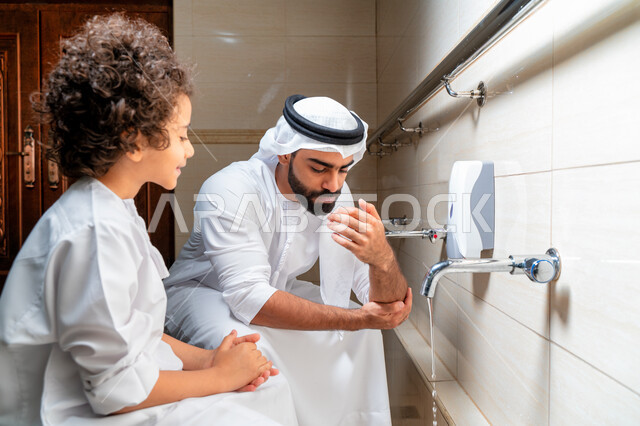رجل عربي خليجي إماراتي وإبنه في أماكن مخصصة للوضوء في أحد المساجد العربية ، تعلم كيفية الوضوء للأطفال ، الطهارة والوضوء ، مغاسل الوضوء ، أحواض ومغاسل مخصصة للوضوء ، مفهوم أركان الوضوء