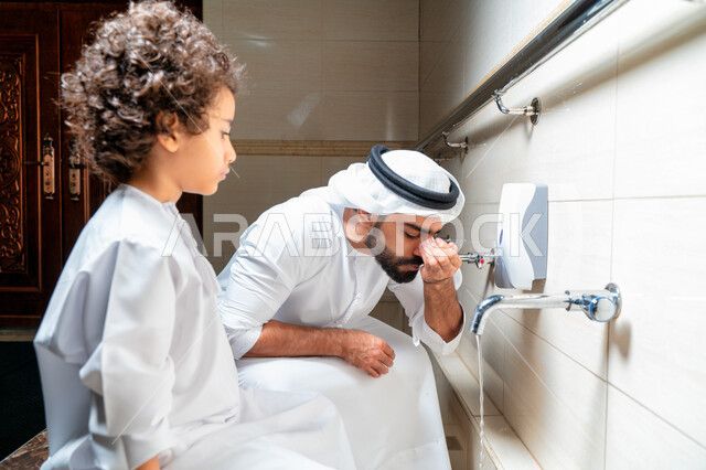رجل عربي خليجي إماراتي وإبنه في أماكن مخصصة للوضوء في أحد المساجد العربية ، تعلم كيفية الوضوء للأطفال ، الطهارة والوضوء ، مغاسل الوضوء ، أحواض ومغاسل مخصصة للوضوء ، مفهوم أركان الوضوء