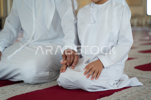 صورة مقربة لرجل عربي خليجي إماراتي وإبنه في أحد المساجد العربية، تعليم أداء فريضة الصلاة، تعليم الصلاة للأطفال، العبادة والتقرب الى الله، أماكن إسلامية مقدسة، مفهوم أركان الإسلام، إسلاميات وعبادة