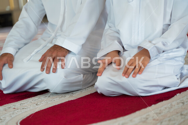 صورة مقربة لرجل عربي خليجي إماراتي وإبنه في أحد المساجد العربية، تعليم أداء فريضة الصلاة، تعليم الصلاة للأطفال، العبادة والتقرب الى الله، أماكن إسلامية مقدسة، مفهوم أركان الإسلام، إسلاميات وعبادة