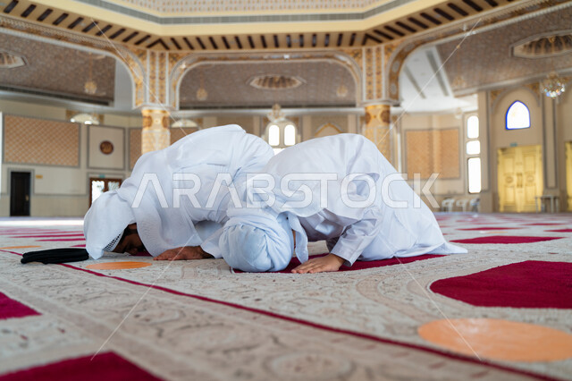 رجل عربي خليجي إماراتي وإبنه في أحد المساجد العربية، أداء فريضة الصلاة، السجود في الصلاة، تعليم الصلاة للأطفال، العبادة والتقرب الى الله، أماكن إسلامية مقدسة، مفهوم أركان الإسلام، إسلاميات وعبادة