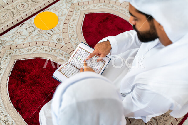 صورة مقربة لرجل عربي خليجي إماراتي وإبنه في أحد المساجد العربية، يحمل بيده المصحف الشريف ، قراءة القرآن الكريم ، تلاوة القرآن الكريم ، تحفيظ القرآن الكريم للأطفال ، العبادة والتقرب الى الله ، أماكن إسلامية مقدسة ، إسلاميات وعبادة