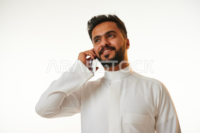 بورتريه لشاب عربي خليجي سعودي يقوم بإجراء مكالمة هاتفية، التواصل مع الأفراد، اتصال وتواصل، علاقات اجتماعية، دردشة وتعارف، التواصل الإجتماعي، خلفية بيضاء