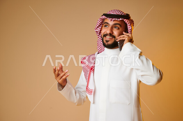 Portrait of a Saudi Arab Gulf youth making a phone call, communicating with individuals, communication and communication, social relations, chat and acquaintance, social communication, colored background