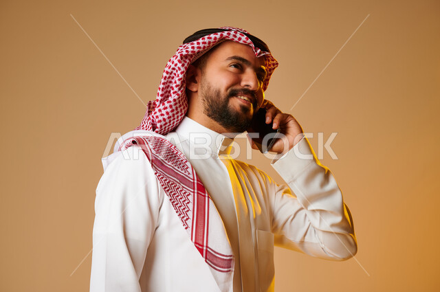 Portrait of a Saudi Arab Gulf youth making a phone call, communicating with individuals, communication and communication, social relations, chat and acquaintance, social communication, colored background