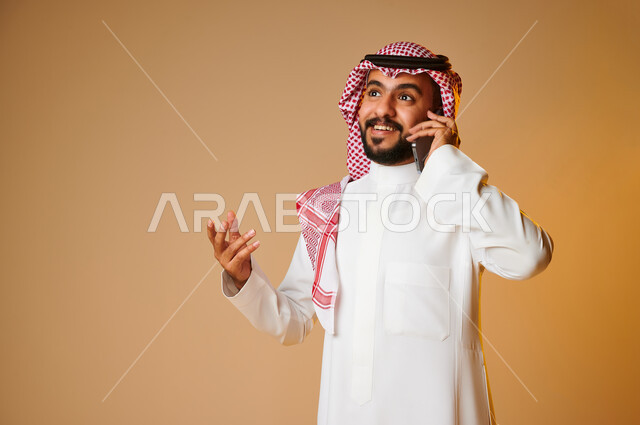 Portrait of a Saudi Arab Gulf youth making a phone call, communicating with individuals, communication and communication, social relations, chat and acquaintance, social communication, colored background