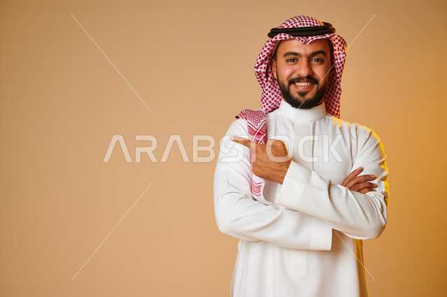 بورتريه لرجل عربي خليجي سعودي يشير باصبع السبابة نحو شيء ما، إيماءات وجه تدل على السعادة، الاشارة نحو شيء ما، خلفية ملونة