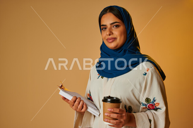 بورتريه لامرأة عربية خليجية سعودية مثقفة تمسك كوب القهوة وتحمل بيدها كتاب، الاستمتاع بشرب القهوة، التطلع للمستقبل، التعليم والدراسة، مفهوم التحضير ومراجعة البحوث العلمية، مفهوم الثقافة والتعليم، هواية القراءة والإطلاع، خلفية ملونة