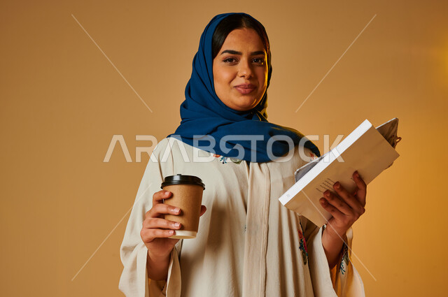 بورتريه لامرأة عربية خليجية سعودية مثقفة تمسك كوب القهوة وتحمل بيدها كتاب، الاستمتاع بشرب القهوة، التطلع للمستقبل، التعليم والدراسة، مفهوم التحضير ومراجعة البحوث العلمية، مفهوم الثقافة والتعليم، هواية القراءة والإطلاع، خلفية ملونة
