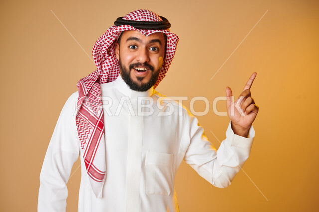 بورتريه لرجل عربي خليجي سعودي يشير باصبع السبابة للاعلى، الاشارة الى شيء ما، ايماءات وجه تدل على الدهشة، التعجب والاستغراب، حركة اصبع واشارات، خلفية ملونة