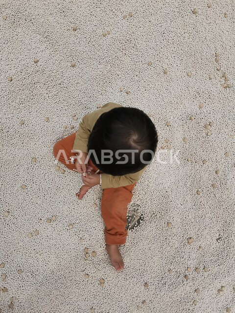 صورة من الاعلى لطفل صغير يجلس على الارض، طفل يمارس الانشطة الترفيهية، روضة أطفال، حضانة أطفال، أنشطة فنية وترفيهية، مراكز تنمية الاطفال 