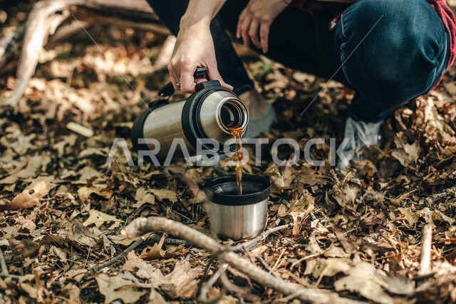 صورة مقربة لرجل يقوم اعداد كوب من الشاي، أوراق أشجار، رحلة تخييم، مشروبات ساخنة، بر وتخييم، فصل الخريف