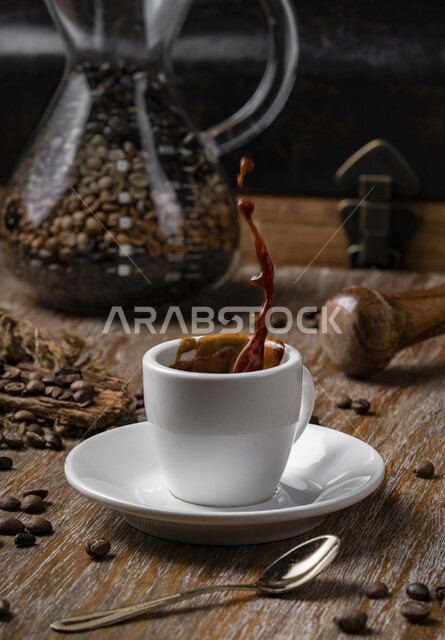 صورة مقربة لفنجان السادة ، قهوة اسبريسو ، مشروبات ساخنة ، فنجان القهوة الساخن ، حبوب البن المتناثرة على سطح خشبي ، وعاء قهوة زجاجي 