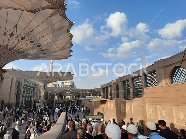 تجمع المسلمون في المجمع الخارجي للمسجد النبوي في المدينة المنورة بالمملكة العربية السعودية، ساحة المسجد النبوي الشريف، الحرم النبوي الشريف، أماكن إسلامية مقدسة، المظلات الإلكترونية، معالم دينية إسلامية