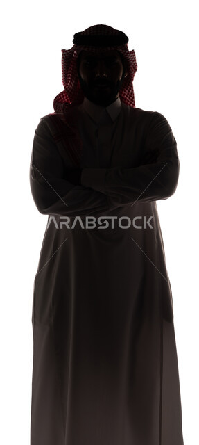 بورتريه ، صورة ظلية لرجل عربي خليجي سعودي ، يرتدي الزي السعودي التقليدي ، يقف بإستقامه بأيدي متقاطعة ، ينظر إلى الكاميرا ، خلفية بيضاء