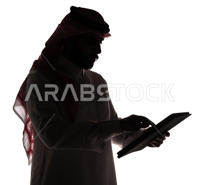 بورتريه ، صورة ظلية لرجل عربي خليجي سعودي ، إستخدام جهاز تقني التابلت ، تصفح الإنترنت ، إستخدام اجهزة تقنية حديثة ، العمل عن بعد ، التسويق الإلكتروني ، مهن ووظائف ، خلفية بيضاء