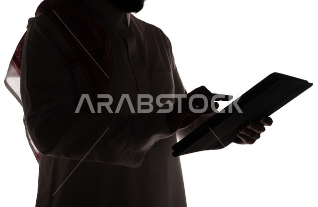 بورتريه ، صورة ظلية لرجل عربي خليجي سعودي ، إستخدام جهاز تقني التابلت ، تصفح الإنترنت ، إستخدام اجهزة تقنية حديثة ، العمل عن بعد ، التسويق الإلكتروني ، مهن ووظائف ، خلفية بيضاء