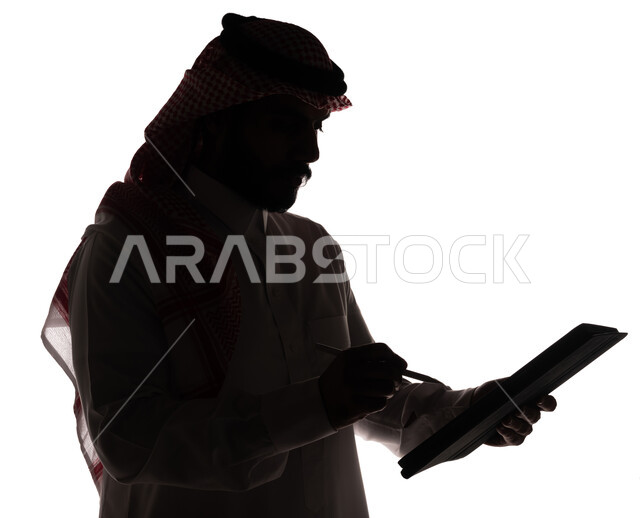 بورتريه ، صورة ظلية لرجل عربي خليجي سعودي ، إستخدام جهاز تقني التابلت ، تصفح الإنترنت ، إستخدام اجهزة تقنية حديثة ، العمل عن بعد ، التسويق الإلكتروني ، مهن ووظائف ، خلفية بيضاء