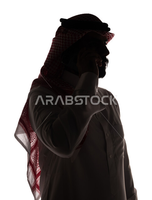 بورتريه ، صورة ظلية لرجل عربي خليجي سعودي ، إجراء مكالمة هاتفية بإستخدام الهاتف المحمول ، إستخدام اجهزة تقنية حديثة ، الإتصال والدردشة ، التواصل الإجتماعي ، خلفية بيضاء