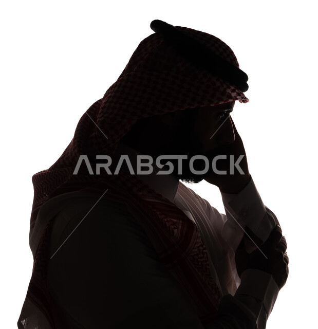بورتريه ، صورة ظلية لرجل عربي خليجي سعودي ، إجراء مكالمة هاتفية بإستخدام الهاتف المحمول ، إستخدام اجهزة تقنية حديثة ، الإتصال والدردشة ، التواصل الإجتماعي ، خلفية بيضاء
