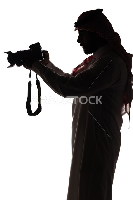 بورتريه ، صورة ظلية لرجل عربي خليجي سعودي ، يحمل بيده كاميرا تصوير عالية الدقة ، إلتقاط الصور التذكارية ، مصور سعودي ، إحتراف التصوير ، كاميرا عالية الدقة ، هواية التصوير ، خلفية بيضاء