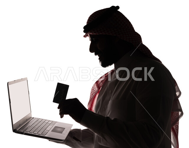 بورتريه ، صورة ظلية لرجل عربي خليجي سعودي ، إستخدام جهاز الحاسوب المحمول ، البطاقة البنكية الإلكترونية ، التسويق الإلكتروني ، مهن ووظائف ، طلبات الأونلاين ، الدفع عن طريق بطاقة الإئتمان ، خلفية بيضاء