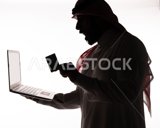 بورتريه ، صورة ظلية لرجل عربي خليجي سعودي ، إستخدام جهاز الحاسوب المحمول ، البطاقة البنكية الإلكترونية ، التسويق الإلكتروني ، مهن ووظائف ، طلبات الأونلاين ، الدفع عن طريق بطاقة الإئتمان ، خلفية بيضاء