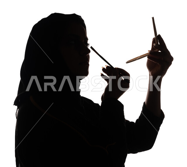 بورتريه ، صورة ظلية لمرأة عربية خليجية سعودية ، إستخدام إحدى أدوات التجميل ( فرشاة ظل العيون ) ، التسويق لمنتجات التجميل ، الإهتمام بالجمال والمظهر الخارجي ، أدوات مكياج تتوريال ، خلفية بيضاء