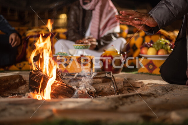 مجموعة من الاصدقاء العرب الخليجيين السعوديين بايماءات تدل على البرد الشديد، ارتداء ملابس الشتاء الدافئة، التدفئة من خلال شعلة النار، حوارات ونقاشات بين الاصدقاء، خيام شعبية في صحاري السعودية، كشتة بر شبابية مسائية، اجواء شتوية ليلية