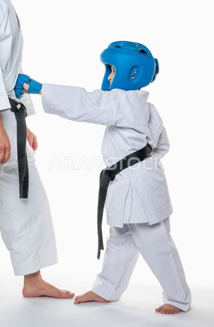 زي الكاراتيه الابيض مع الحزام الاسود, بورتريه لولد عربي خليجي سعودي يقوم بالتدرب على حركات رياضة الكاراتيه ,ممارسة رياضة التايكواندو, فنون الدفاع عن النفس, صورة الجسم بالطول الكامل, خلفية بيضاء .