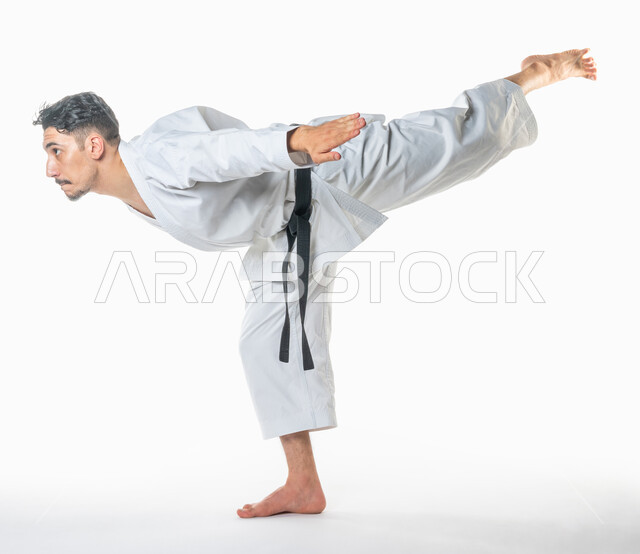 بورتريه جانببي لرجل عربي خليجي سعودي يمارس رياضة الكاراتيه اليابانية، رياضة التايكواندو, زي الكاراتيه الأبيض مع الحزام الأسود، التدرب على حركات قتالية خاصة، فنون الدفاع عن النفس، بطولات رياضة الكاراتيه، صورة الجسم بالطول الكامل, خلفية بيضاء