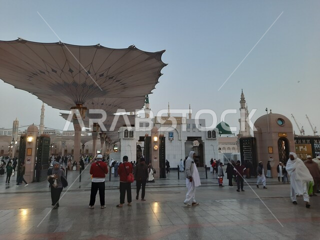 Muslims gather in the outer complex of the Prophet’s Mosque in Madinah, Kingdom of Saudi Arabia, the square of the Prophet’s Mosque, the Prophet’s Noble Sanctuary, Islamic holy places, the minaret of the mosque, Islamic religious landmarks