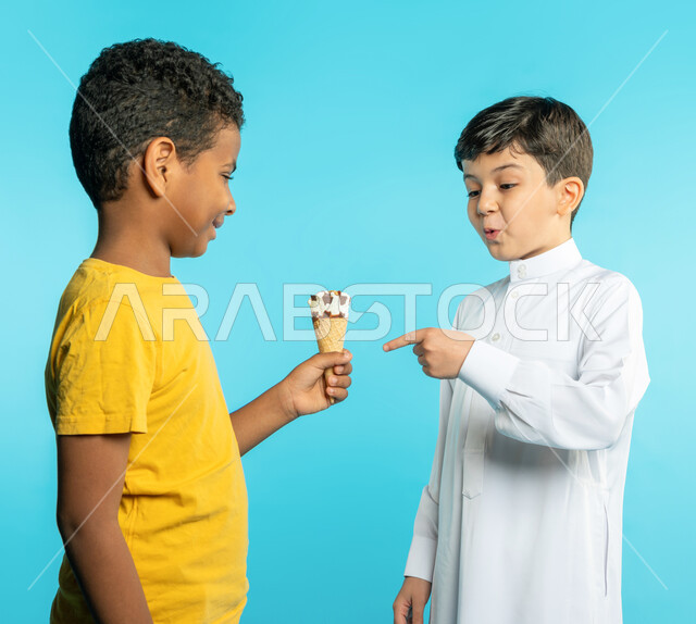 Portrait of two Saudi Arabian Gulf children, serving fresh ice cream, a child pointing towards an ice cream with a facial expression of surprise, summer refreshments, cool summer desserts, blue background