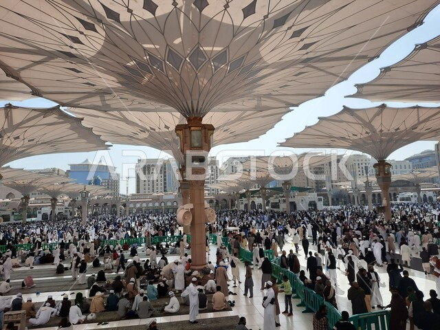 تجمع المسلمون في المجمع الخارجي للمسجد النبوي في المدينة المنورة بالمملكة العربية السعودية، ساحة المسجد النبوي الشريف، الحرم النبوي الشريف، أماكن إسلامية مقدسة، المظلات الالكترونية، معالم دينية إسلامية