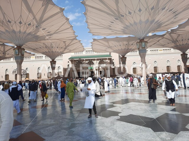 تجمع المسلمون في المجمع الخارجي للمسجد النبوي في المدينة المنورة بالمملكة العربية السعودية، ساحة المسجد النبوي الشريف، الحرم النبوي الشريف، أماكن إسلامية مقدسة، المظلات الالكترونية، معالم دينية إسلامية