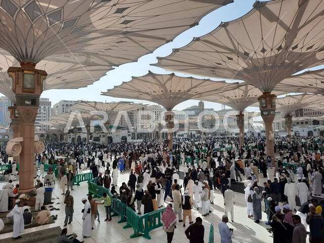 تجمع المسلمون في المجمع الخارجي للمسجد النبوي في المدينة المنورة بالمملكة العربية السعودية، ساحة المسجد النبوي الشريف، الحرم النبوي الشريف، أماكن إسلامية مقدسة، المظلات الالكترونية، معالم دينية إسلامية